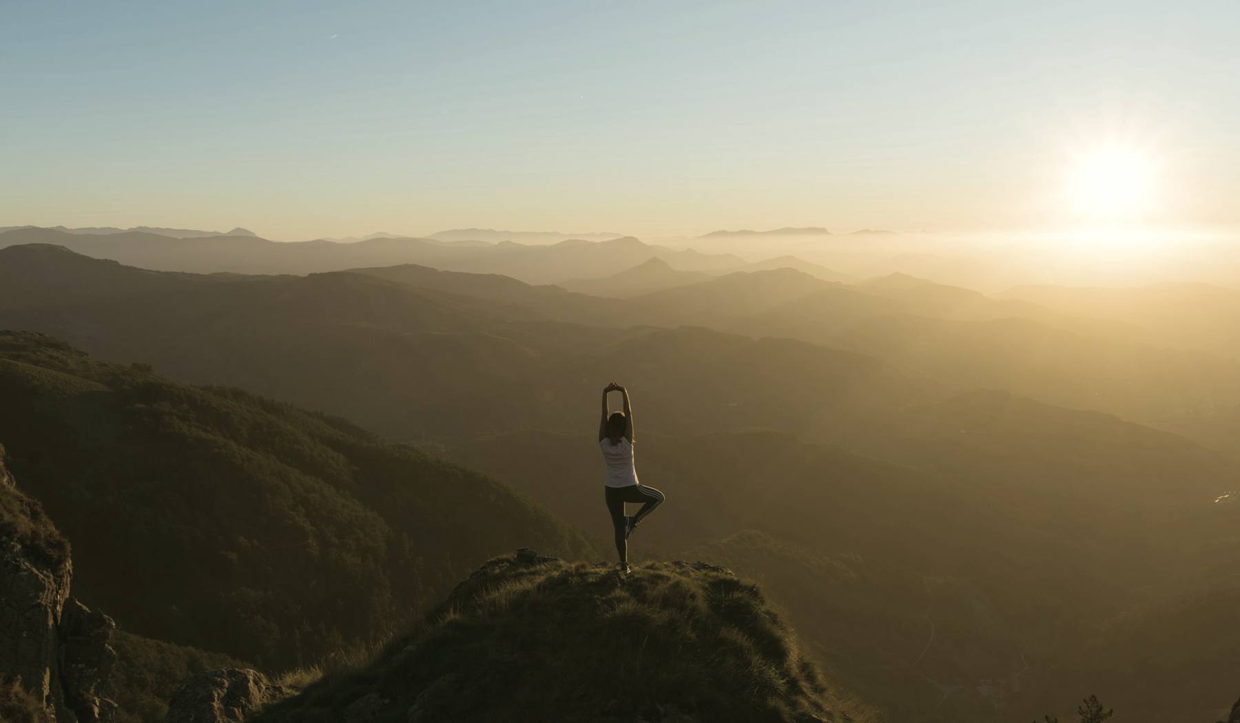 Amanecer sobre la cordillera, una mujer en postura de yoga